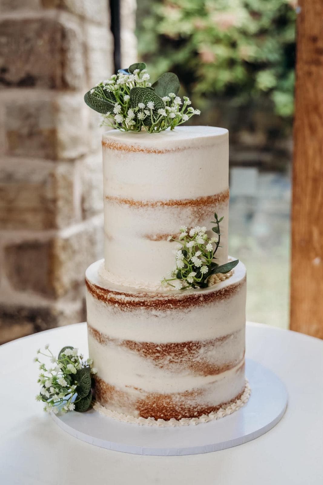 Semi-naked two tier wedding cake with fresh flowers