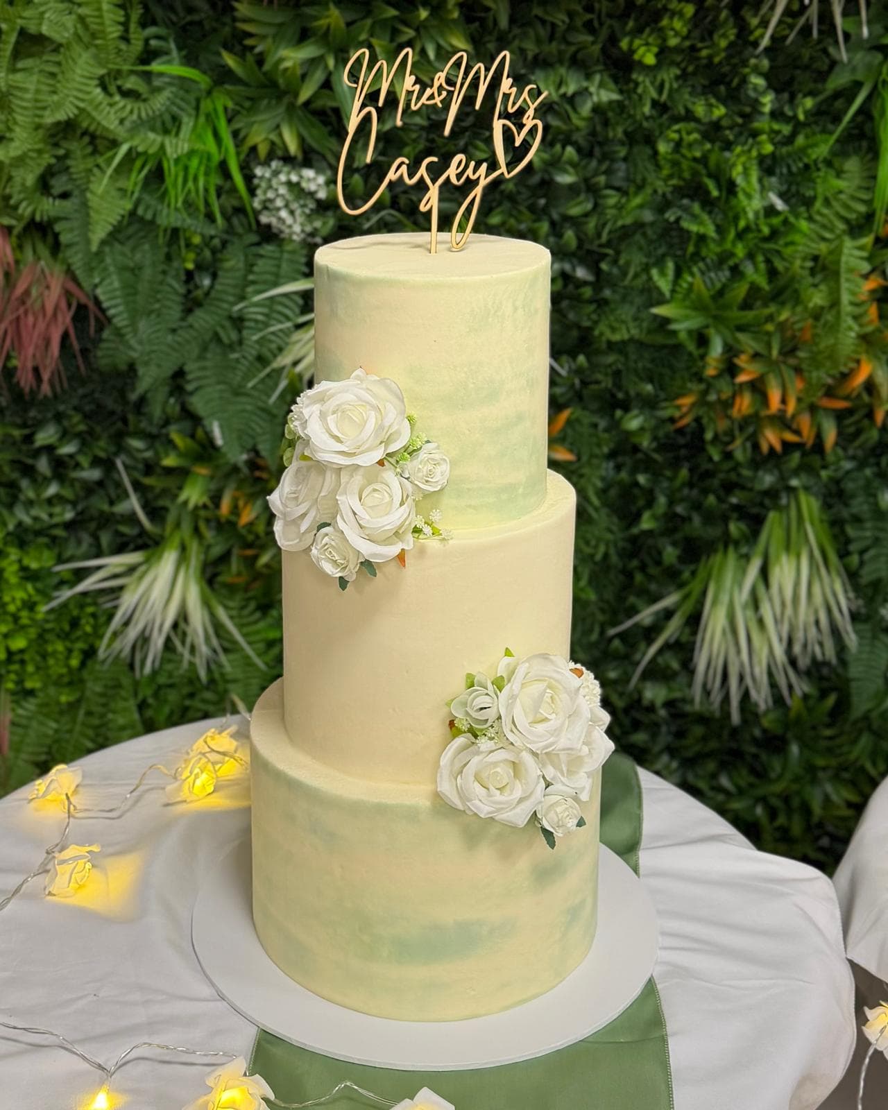 Two tier wedding cake with white roses and a name topper